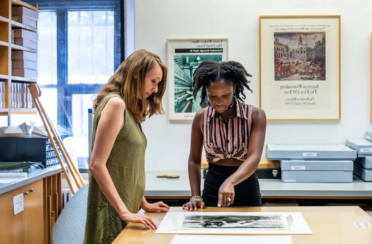 A student and internship supervisor looking at a photo on a table in a museum.
