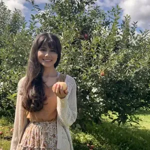 24岁的Gloria Parrales微笑着在果园里拿着一个苹果