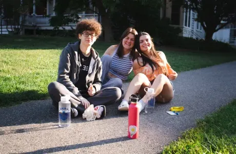 三个学生拿着水瓶坐在地上.