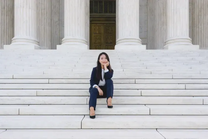 一个学生穿着西装坐在最高法院的台阶上.
