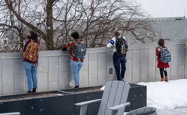 学生们站在尼尔森图书馆的屋顶上，从图书馆的边缘往外看